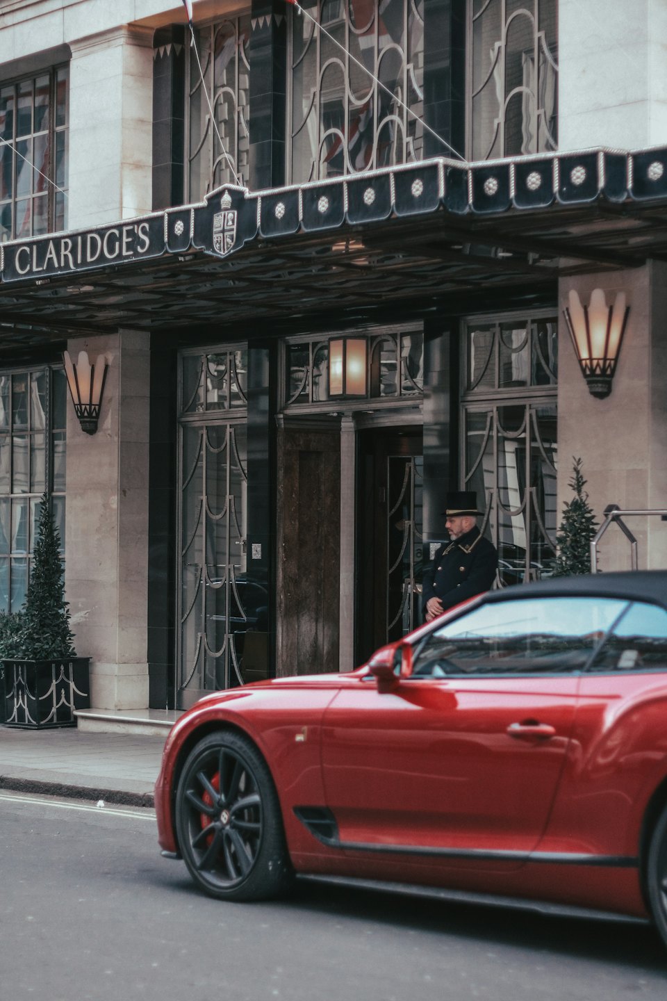 Un portier en uniforme se tient devant l'entrée d'un hôtel de luxe.