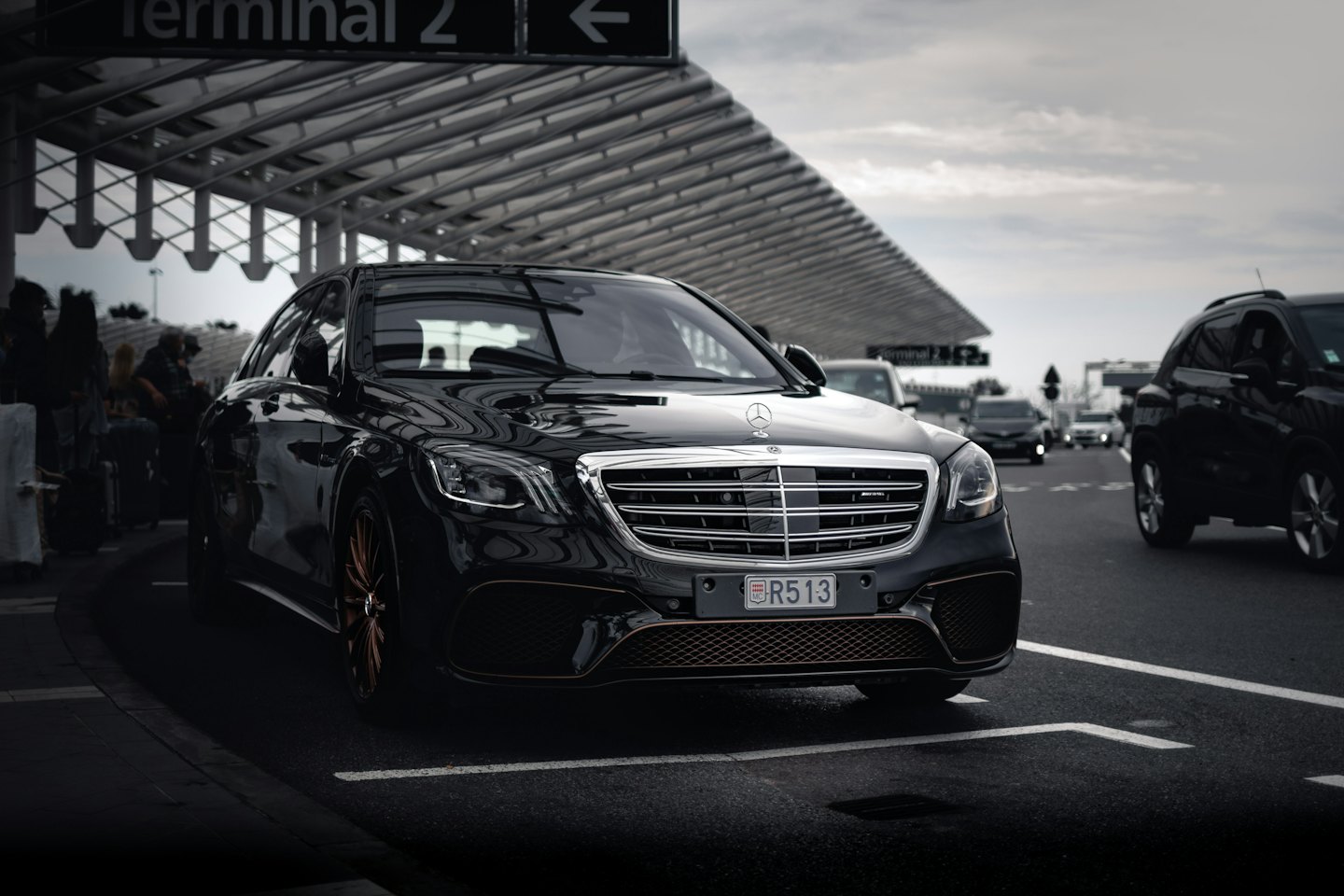 Mercedes noire garée sous un auvent à l'aéroport.