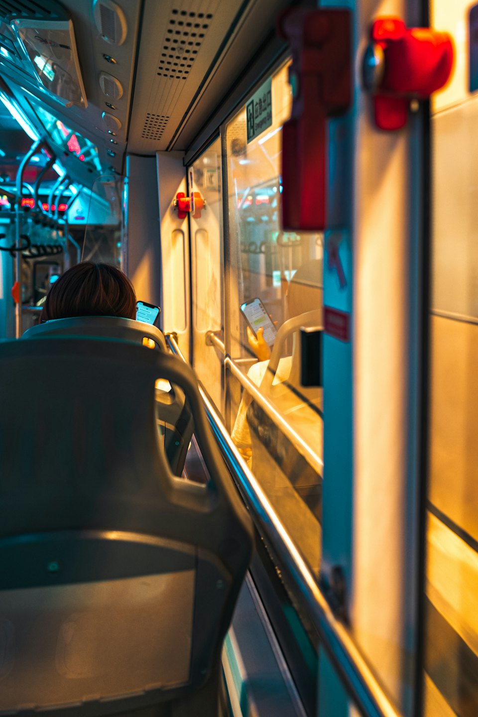 Une personne dans un bus regarde son téléphone avec les lumières de la ville à l'extérieur.