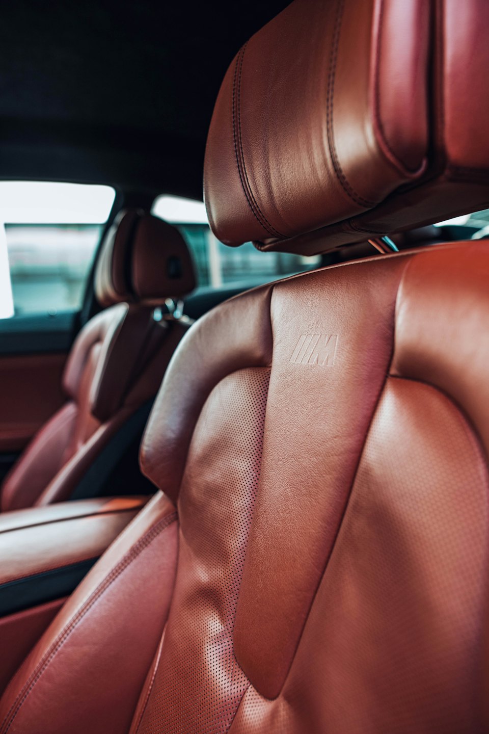 Sièges de voiture en cuir marron avec surpiqûres détaillées et logos en relief.